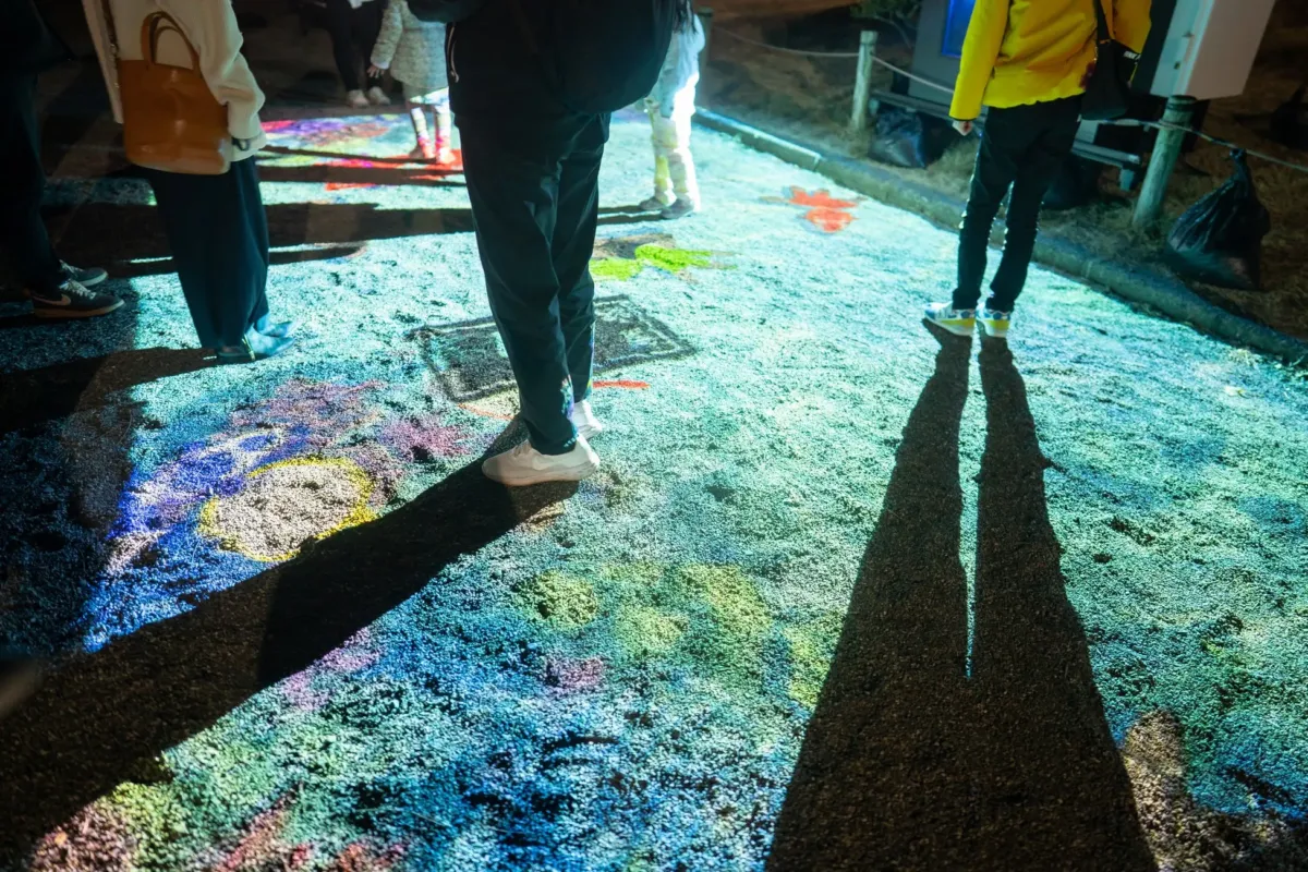 カラフルな光が地面に投影され、人々が立っている様子