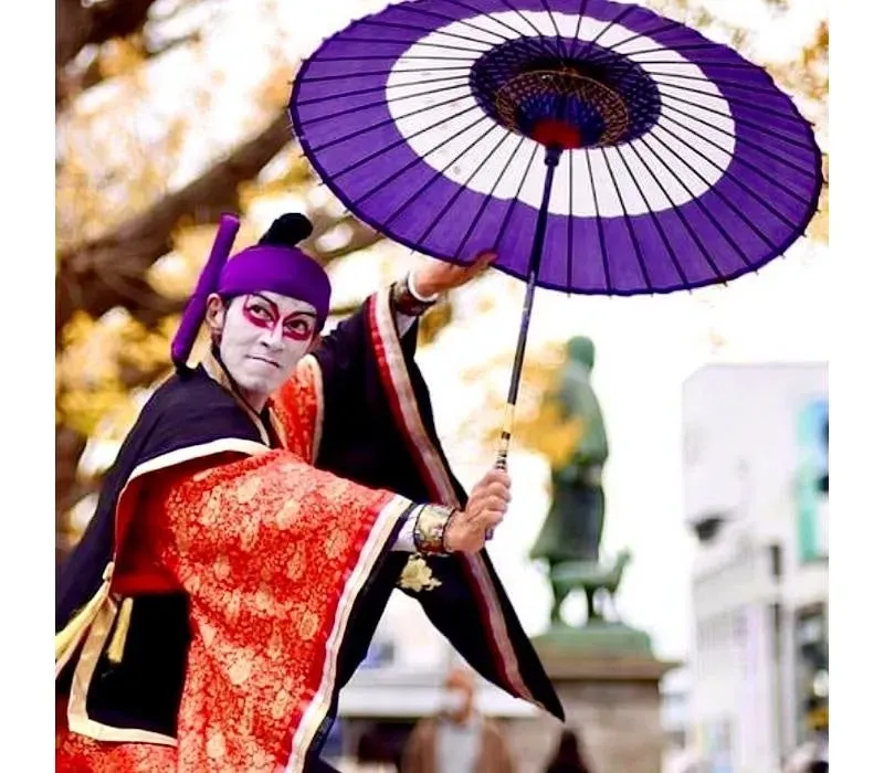 歌舞伎役者が紫色の傘を持ってポーズ
