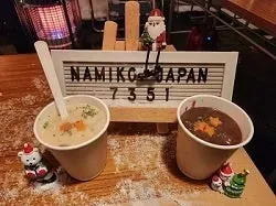 クリスマスの装飾が施されたテーブルの上に、スープが入った紙コップが2つ並んでいます。