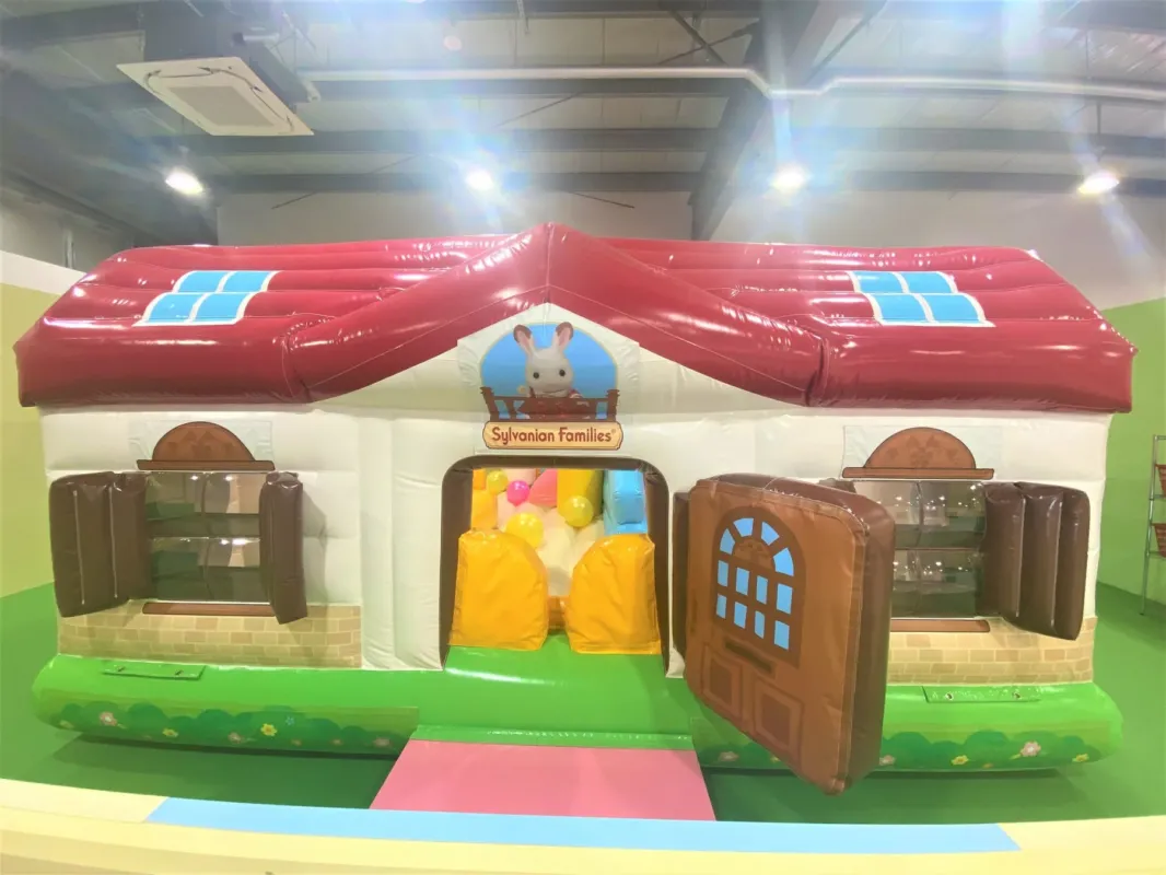 シルバニアファミリーの家を模した、子供向けの遊具です。赤い屋根と白い壁が特徴で、入り口にはドアと窓があります。中にはボールや黄色い袋が置かれています。