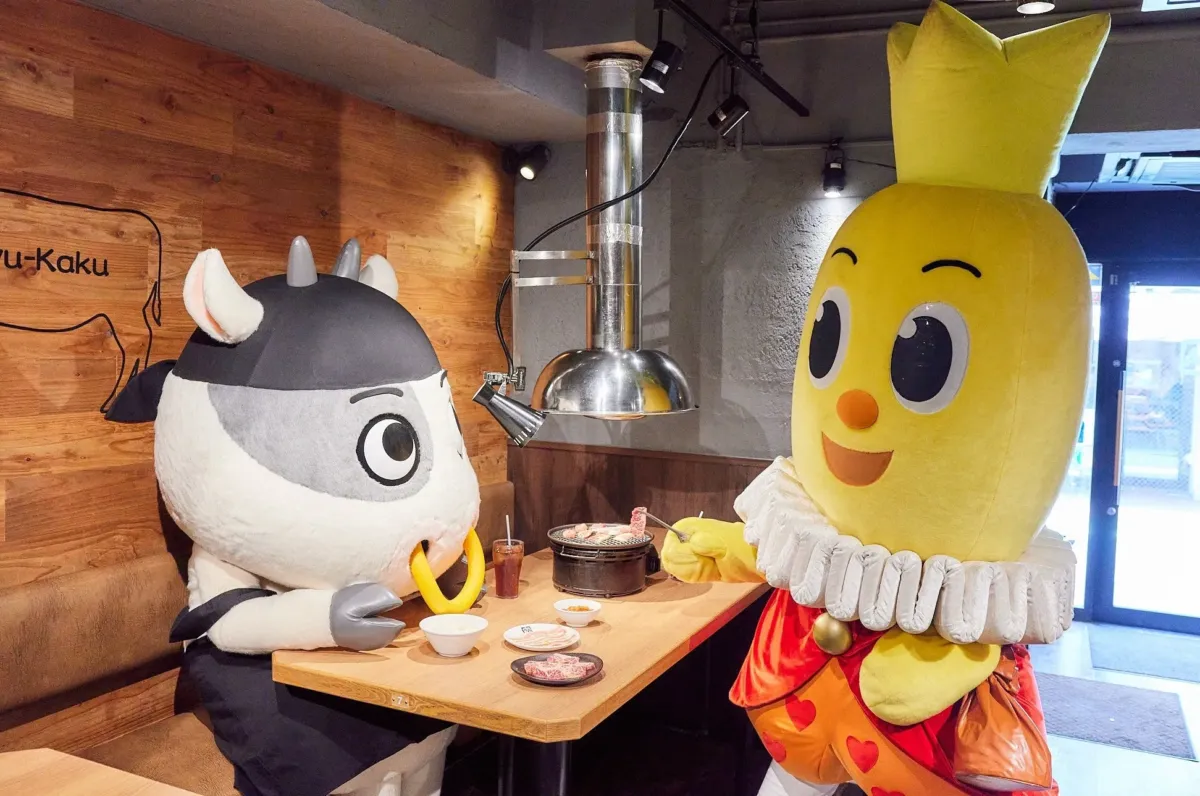 焼肉店で食事をする牛の着ぐるみと黄色いキャラクターの画像